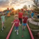 A cheerful mini golf course with families and friends playing together, featuring colorful obstacles and bright green turf.